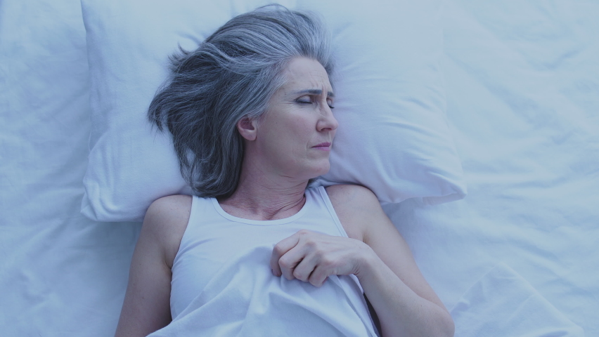 Tired unhappy aged woman lying in bed trying to fall asleep, suffering insomnia Royalty-Free Stock Footage #1068244208