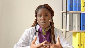 Young african american woman doctor having chat or consultation on laptop looking directly to the camera