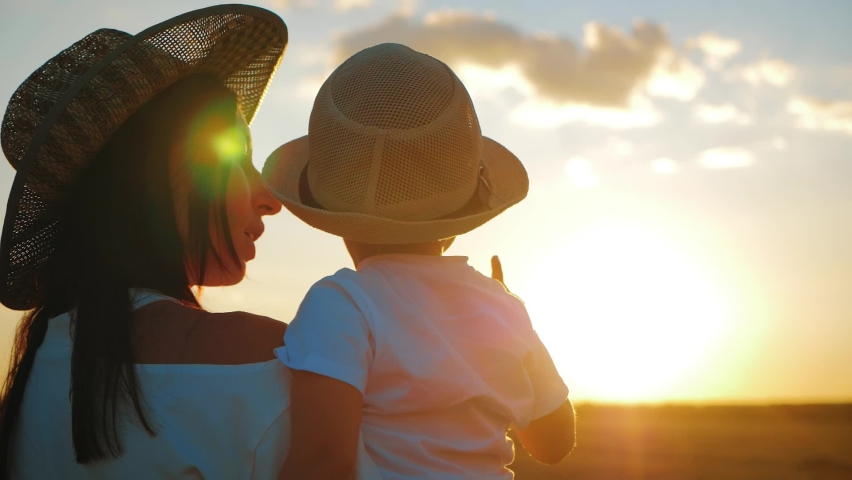 Happy family mom and little son at sunset silhouette. Mother and kid reach out to the sun. The concept of a happy family and togetherness with nature.
