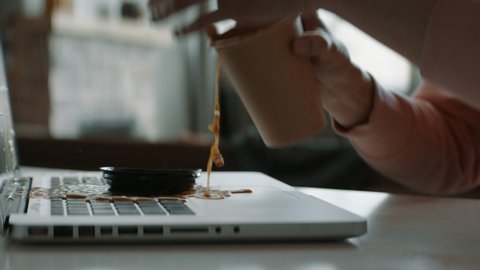 CU Caucasian female working from home, spills coffee on keyboard of her laptop. Shot with 2x anamorphic lens
