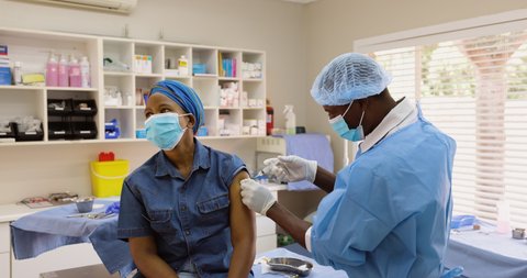 Black African male doctor nurse gives a Black African female patient the Covid-19 vaccine injection