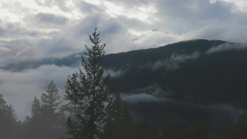Dramatic Scenic Nature Panoramic View of Canadian Mountain Landscape covered in clouds. Artistic Render. Located near Squamish and Whistler, British Columbia, Canada.