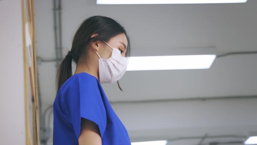 Tired and frustrated young Asian female doctor wearing uniform and surgical mask suffering from neck pain while working in hospital during covid-19 outbreak Royalty-Free Stock Footage #1068262634
