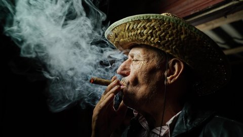 Tobacco farmer. The man is enjoying tobacco. Evening at the ranch. Cigarette smoke is in the air. Successful tobacco business.