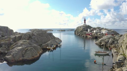 Svenner Lighthouse oceans edge, on Norwegian island, idyllic bay with boat travellers, sailboat marina, push in drown footage