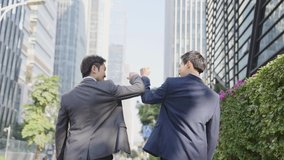 rear view of two asian businessmen talking while walking on street in modern city - Powered by Shutterstock - Get 15% off with code: PIKWIZARD15