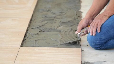 Repairs laying of a ceramic tile on a concrete floor with use of trowel and glue mixes