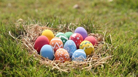 Happy Easter Day. Easter eggs on green grass background, Dolly shot. Camera moving through colorful easter eggs in nest on fresh green grass in morning.