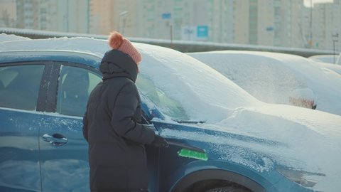 Sweep Snow From Automobile With Brushes In Winter.Scraping Ice. Scratching Ice From Car Window In Winter.Brushing Snow And Ice From Car Glass.Female Cleaning Fresh Snow After Snowstorm From Vehicle.