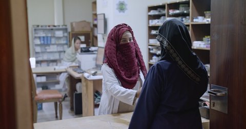 Muslim female hospital pharmacist in veil dispensing medicine and counseling a customer at an in-patient pharmacy at a hospital. Islamabad, Pakistan, 2nd March 2020.