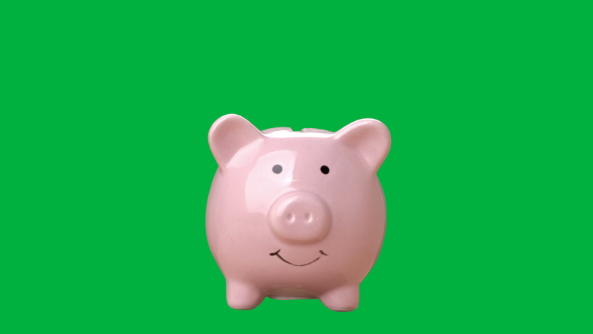 Hand is putting a coin or money in a piggy bank on chroma key green screen background. Saving money concept. Royalty-Free Stock Footage #1068291197