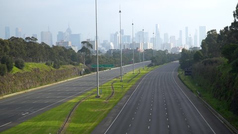 Car drives down an eerily empty highway during the COVID-19 lockdown - shot in Melbourne, Australia, but can represent many city skylines and the impact of coronavirus around the world.