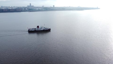 Wirral , Liverpool , United Kingdom (UK) - 02 06 2021: Aerial view following Mersey commuter passenger ferry in shimmering river to Woodside terminal Wirral