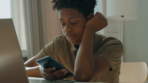 DX Portrait of African American Black kid boy using his phone at home. Shot with 2x anamorphic lens