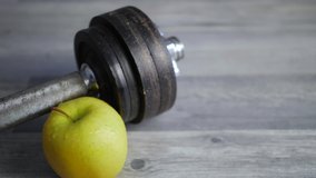 Close-up of green apple and dumbbell on wooden floor