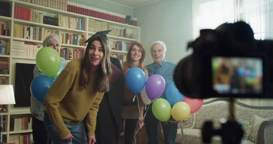 Cinematic shot of happy smiling family members with colorful balloons making family photo portrait together with camera on tripod with timer during celebration mother wife graduation party at home. Royalty-Free Stock Footage #1068310724