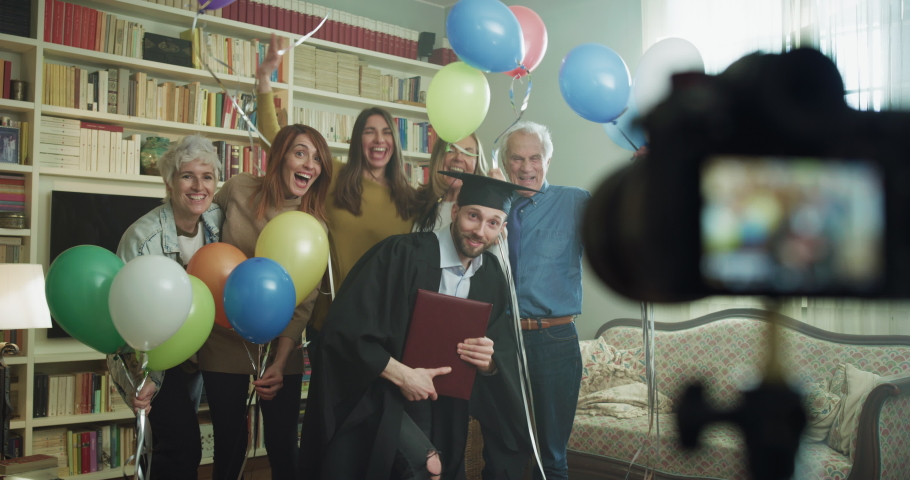 Cinematic shot of happy smiling family members with colorful balloons making family photo portrait together with camera on tripod with timer during celebration son brother graduation party at home. Royalty-Free Stock Footage #1068310727