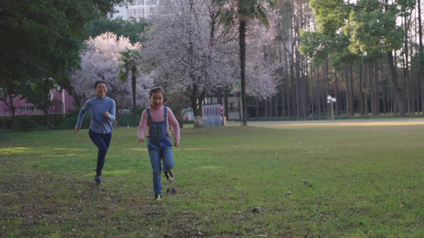4k slow motion of happy asian woman running after her daughter outdoor in the spring park mother playing game with child joyful lifetyle in the nature