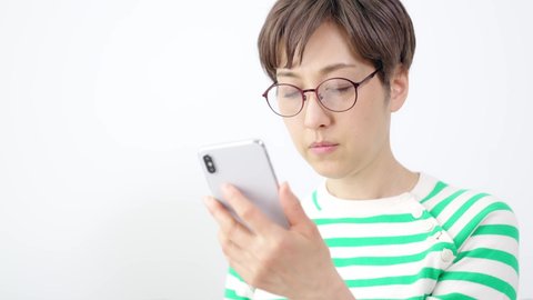 Middle-aged Asian woman with presbyopia who cannot read the text on her smartphone.