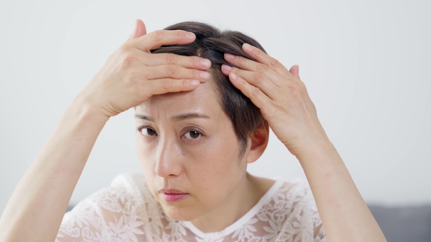 Middle aged Asian woman worrying about her hair. Beauty concept. Thinning hair. Hair care. Royalty-Free Stock Footage #1068316982