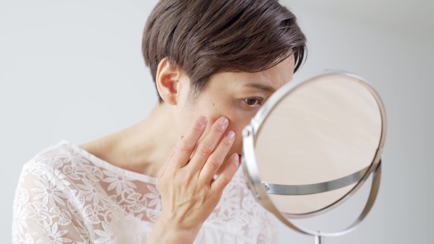 Middle aged Asian woman worrying about her facial skin. Rough skin. Beauty concept. Skin care. | Shutterstock HD Video #1068316991
