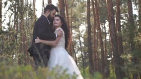 Blurred video. Beautiful wedding couple standing in forest. Lovely newlyweds hugging and kissing on nature. Groom and bride together. Romantic sunset, slow motion. Out of focus video.