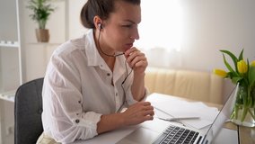 Happy young business woman wears headset talks to web camera making distance online video conference call. Female internet teacher doing distant chat working from home. Telework concept