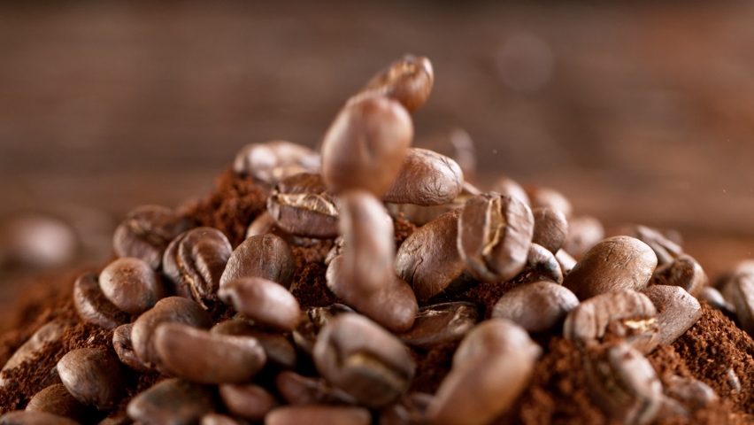 Super Slow Motion Shot of Falling Roasted Coffee Beans into Ground Coffee on Wooden Background at 1000fps Royalty-Free Stock Footage #1068328841