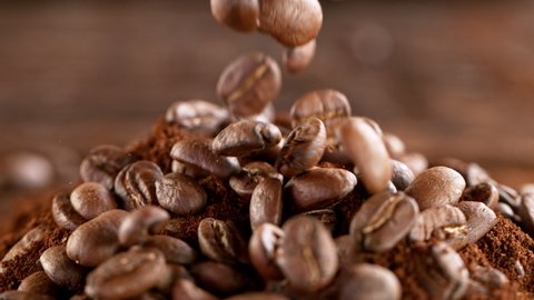 Super Slow Motion Shot of Falling Roasted Coffee Beans into Ground Coffee on Wooden Background at 1000fps