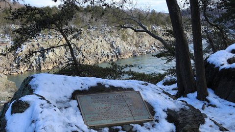 Great Falls, VA - USA - February 3 2021: A commemorative plaque for Stephen T. Mather, first director of the National Park Service. The Potomac River's Mather Gorge is seen in the background.
