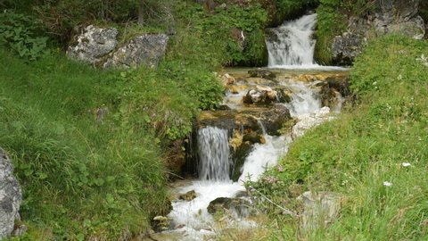 Pure Mineral Spring Water flowing over a small waterfall in a pristine environment in the mountains