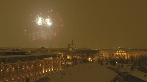 Video filming by a drone of Festive fireworks over the city of St. Petersburg at night in the winter, the Russian Museum and the cathedral Church of the Savior on Blood, Peter and Paul Fortress