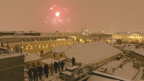 Russia, St.Petersburg, 23 February 2021: Footage by a drone of people on a roof watches fireworks over the city at night in the winter, the Russian Museum, the cathedral Church of the Savior on Blood