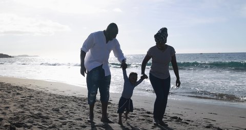 Happy african couple walking on the beach with little son - Black family enjoy vacation together - Love and travel concept 