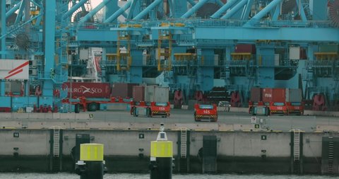 PORT OF ROTTERDAM, THE NETHERLANDS - CIRCA 2019: Automated guided vehicles for moving containers in Rotterdam APM Terminals container hub, self driving electic trucks, intelligent port