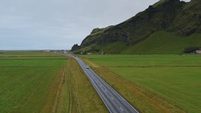 Aerial drone footage of car driving along road in Iceland.