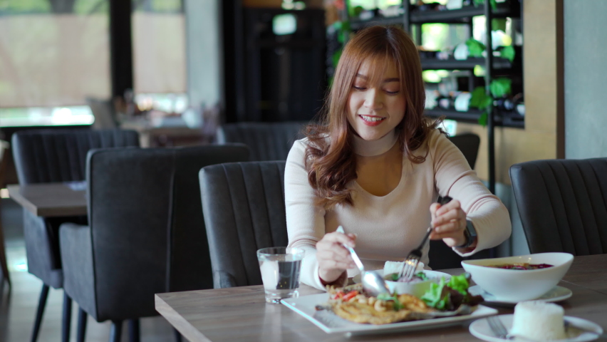 young woman eating with food in restaurant. Royalty-Free Stock Footage #1068343448