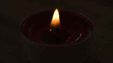 Extreme close-up of a tealight burning in the darkness.