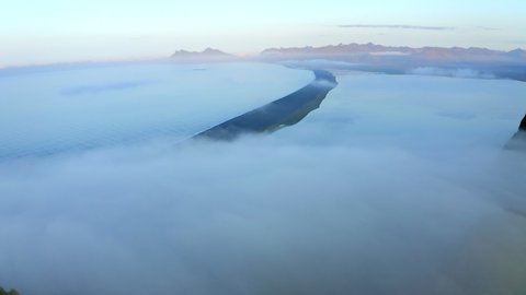 Drone aerial footage of Hvalnes Nature Reserve Beach with cloud inversion beach surrounded by sea in Southern Iceland
