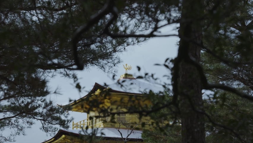 Roof of Kinkaku-Ji Temple in Snow Through Tree Branches