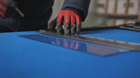 Cutting glass with a glass cutter on a hard blue velvet table.