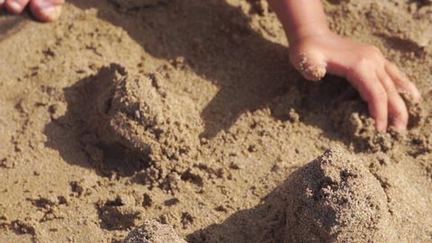 Children playing sand on the beach. Little girl builds sand castle by himself on the beach.