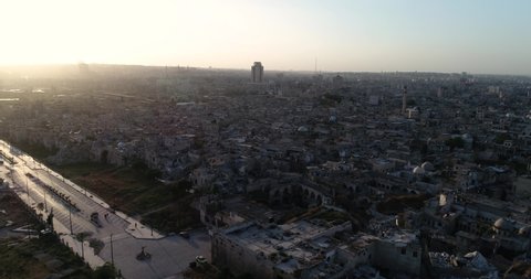 Aerial view above a syrian city under the sunrise. We can see the city of Aleppo all over the horizon 4K