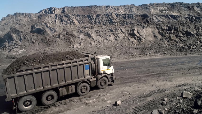 Aerial survey of truck. Dump truck carrying coal along in coal mine. Truck moving on dirt country road. Truck is driving along echnological road. Transportation of coal in trucks on road in open mine  | Shutterstock HD Video #1068354977