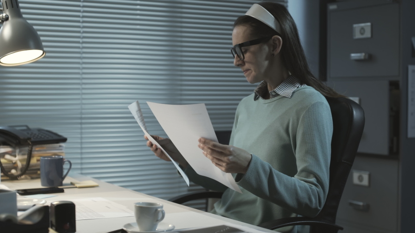 Stressed office worker sitting at desk and working overtime late at night, she is angry and crumples paper sheets Royalty-Free Stock Footage #1068357305
