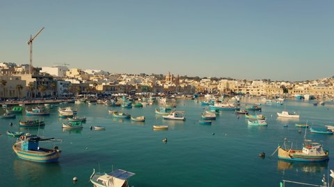 Aerial view of many typical fishing boats and Marsaxlokk city. Malta