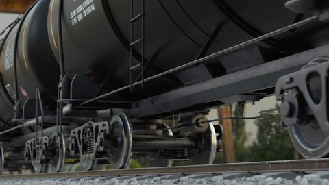 Refinery oil industry and transportation crude fuel by train via railroad. Close up view to the wagon wheels of the cisterns of the freight train near the industrial station, loop 3d animation.