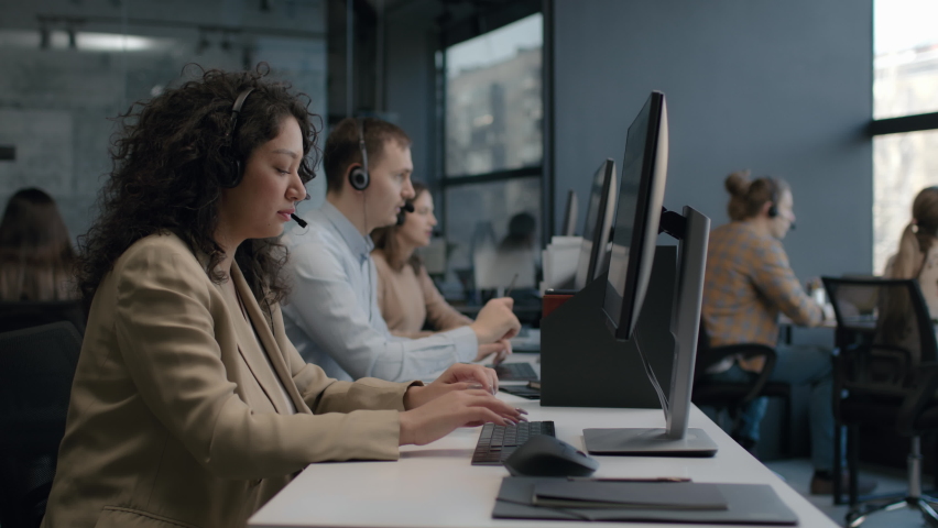 Call center and helpful customer service. Use pc computer and answer questions on phone line at modern co-working. Diverse group of people talks on sale hotline. Busy seller at agency office indoors Royalty-Free Stock Footage #1068362582