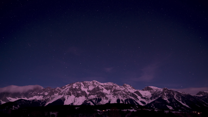 Winter mountain landscape night to day sunrise timelapse with snowy mountains stars and clouds