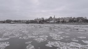 Drone flight over the frozen Vistula River in Warsaw during winter. A large amount of ice floes. The Old Town houses in the background.
